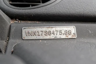 Gros plan sur la plaque VIN gravée sur le tableau de bord d'une voiture, montrant le numéro d'identification du véhicule en détail