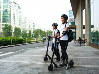 two women riding kick scooters