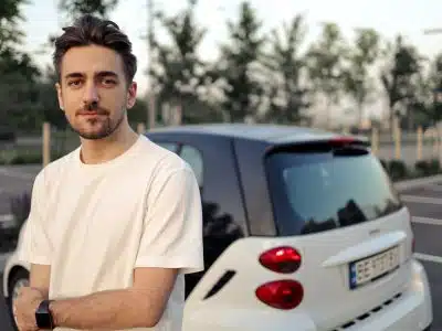 man in white crew neck t-shirt standing beside white car during daytime