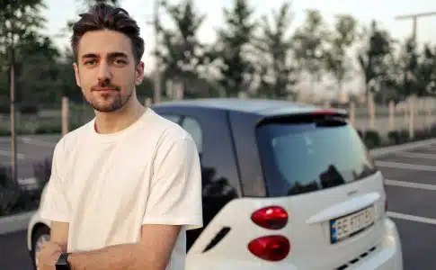 man in white crew neck t-shirt standing beside white car during daytime